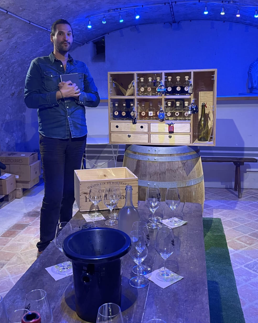 Portrait de Raphaël, Vinothécaire à Sancerre, à côté du Wine Gaming dans l'ambiance bleutée de la cave de sa vinothèque VUE sur Vignes.