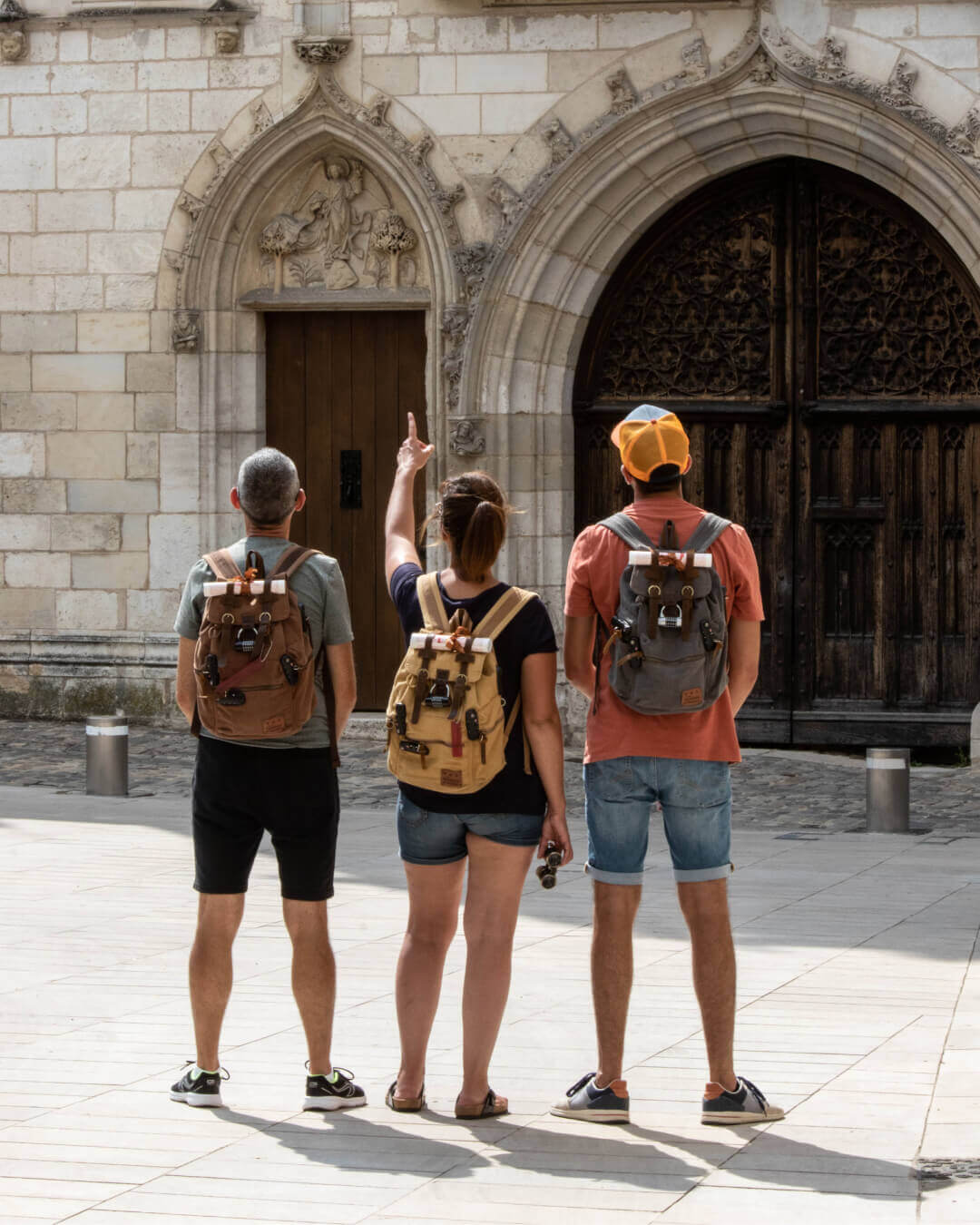 Vue de dos de 3 joueurs, chacun porte un sac de jeu de La grande HisTory, parcours jeu de piste façon escape game à Bourges autour de la vie de Geoffroy Tory