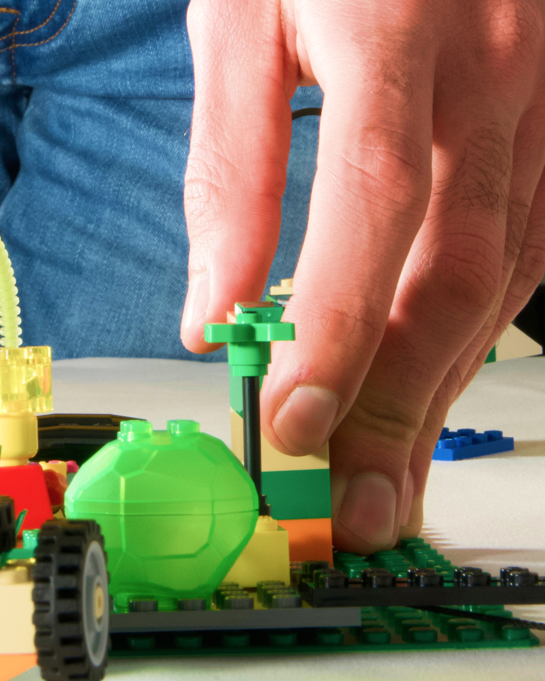 Gros plan sur une main qui pose une brique LEGOⓇ sur une construction existante au cours d'un atelier LEGOⓇ SERIOUS PLAYⓇ à Bourges.